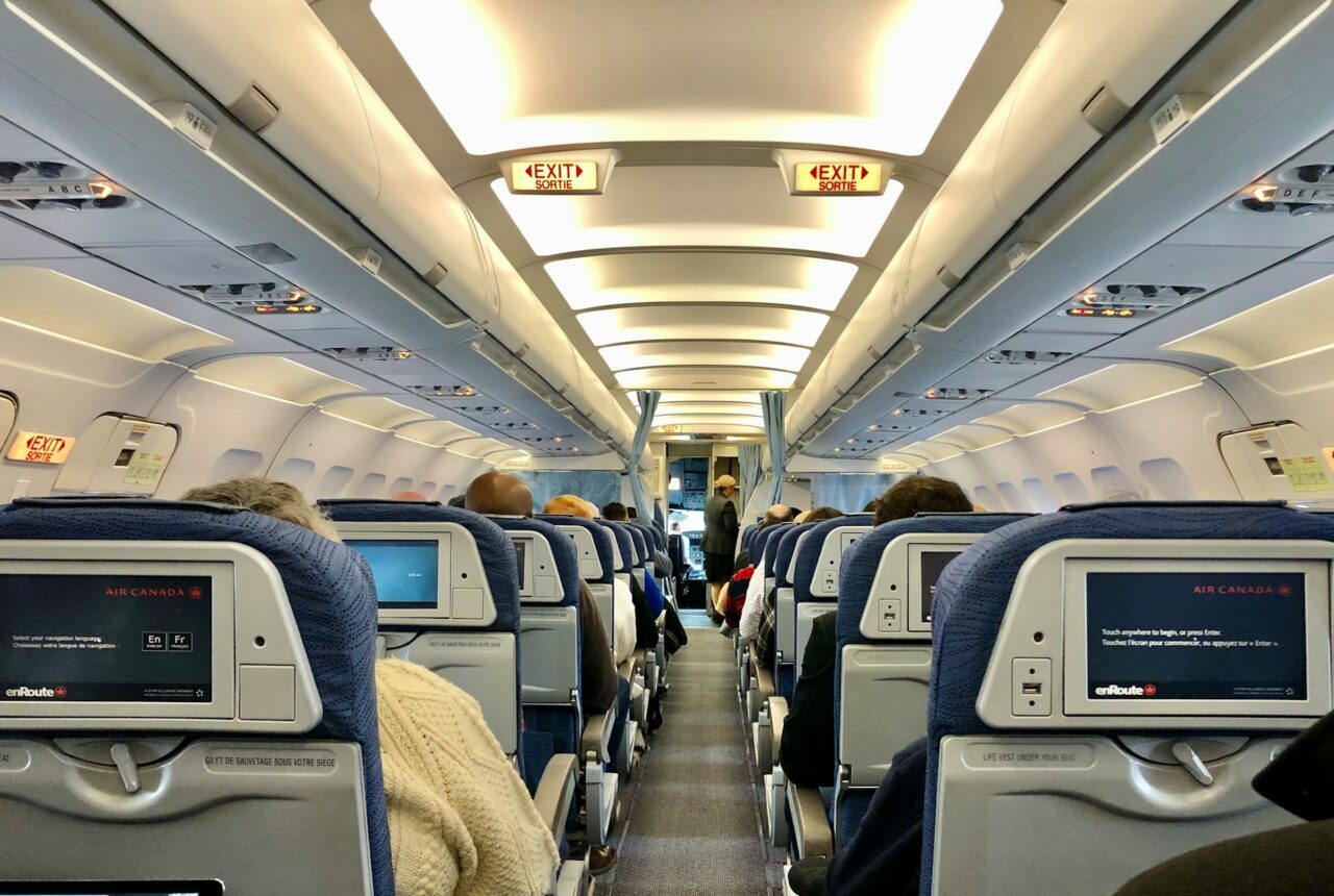 timothee-pineau-GfaSRS_CTS4-unsplash Innenraum eines Flugzeugs mit Passagieren in der Economy Class.
