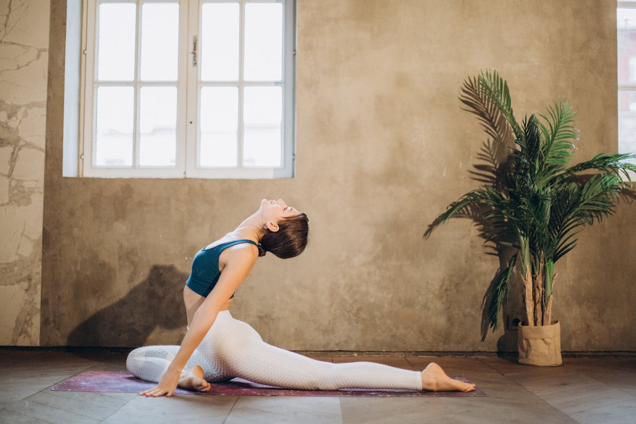 pexels-elly-fairytale-3822138 Frau in aufrechter Taubenpose auf Yogamatte, mit nach hinten gestrecktem Bein und geöffnetem Brustkorb.