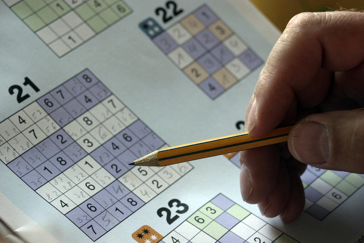 sudoku-552944_1280 Hand einer Person, die mit Bleistift ein Sudoku-Rätsel in einem Heft löst.
