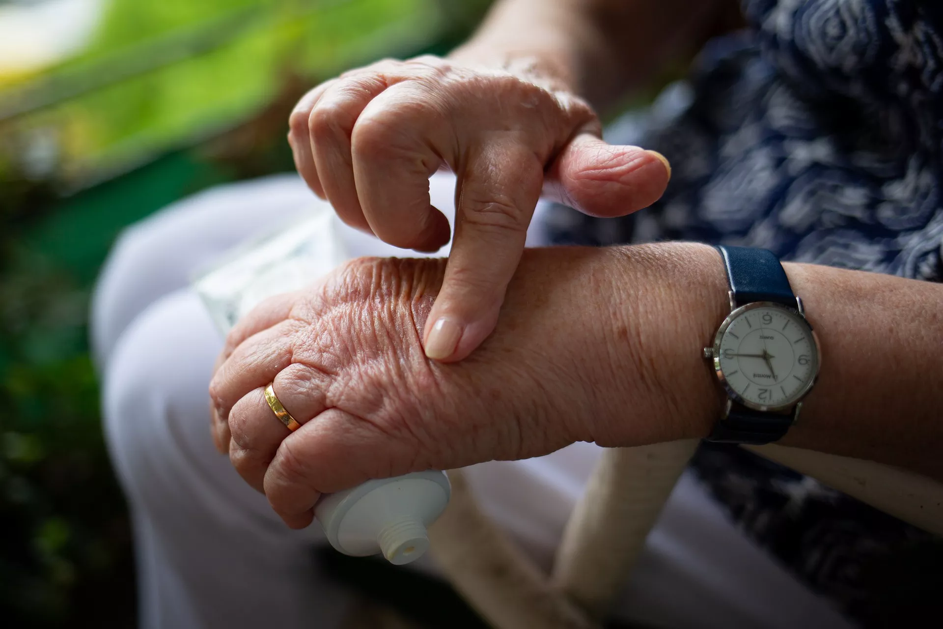 Seniorin berührt ihre linke Hand.