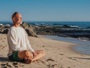 Senior meditiert am Strand