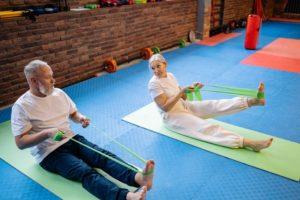 Seniorenpaar beim Stretching der Beine mit einem Theraband